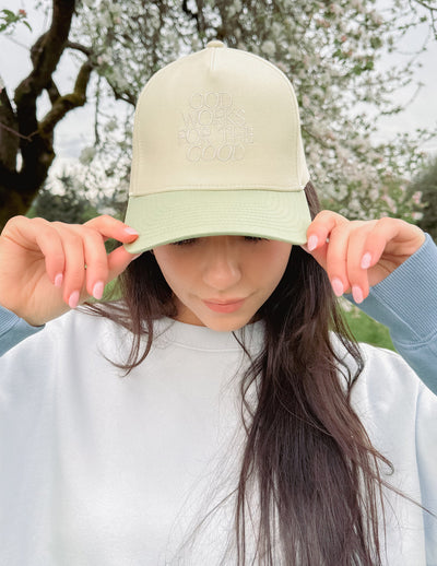 God Works for the Good Trucker Hat